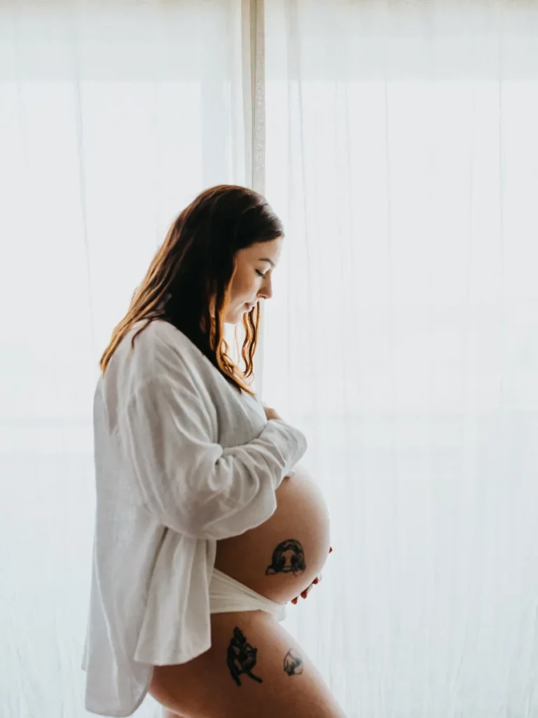 Femme enceinte de profil, caressant son ventre lors d'une séance photo grossesse à Bordeaux.